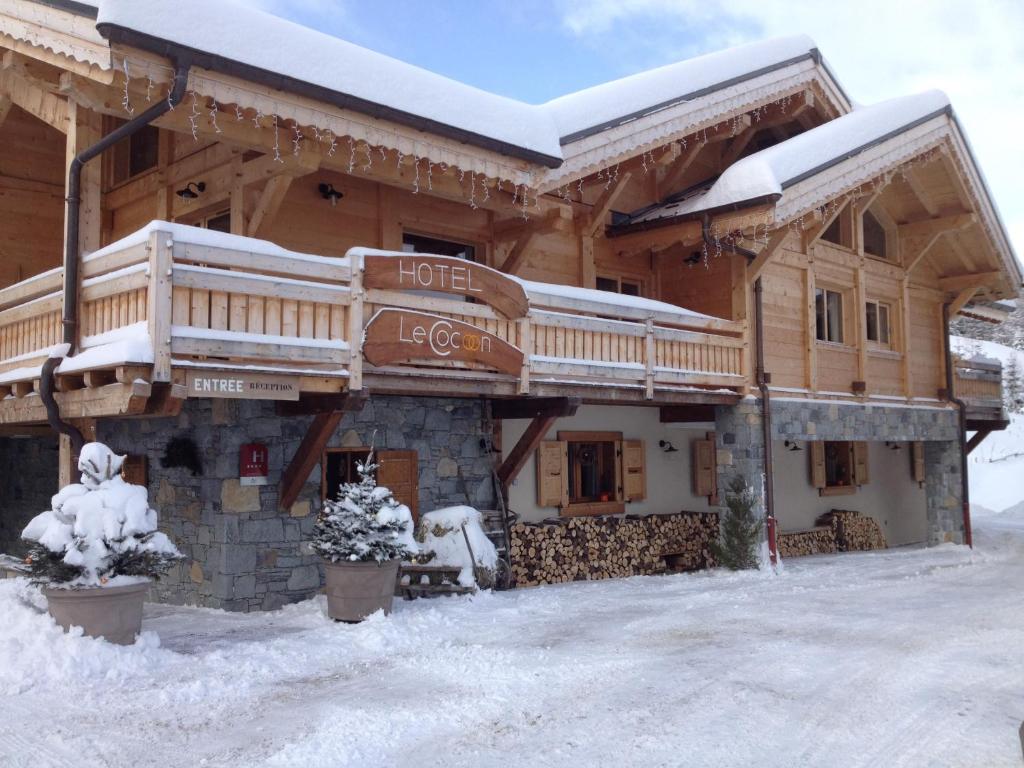 a large wooden building with snow on it at Les Chalets du Cocoon in La Plagne