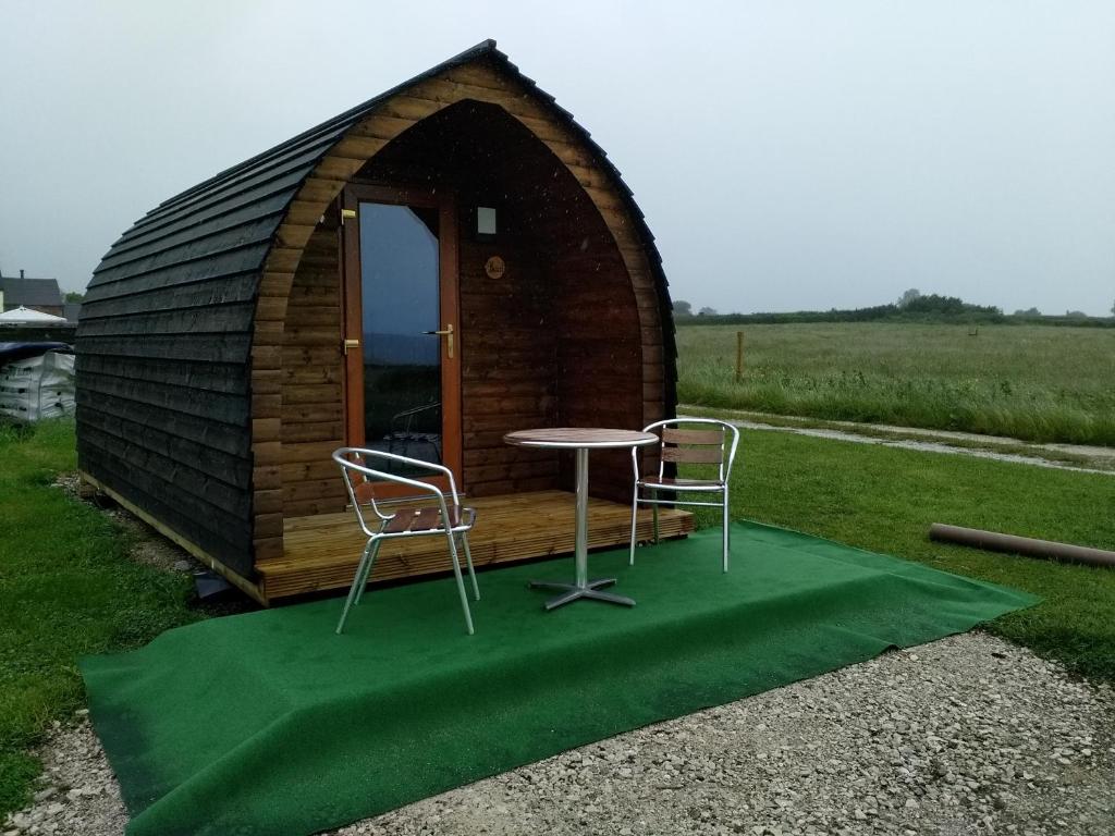 a small wooden cabin with a table and two chairs at Poplars Farm Site Glamping Pods Adults only with separate, private shower rooms in Hulland