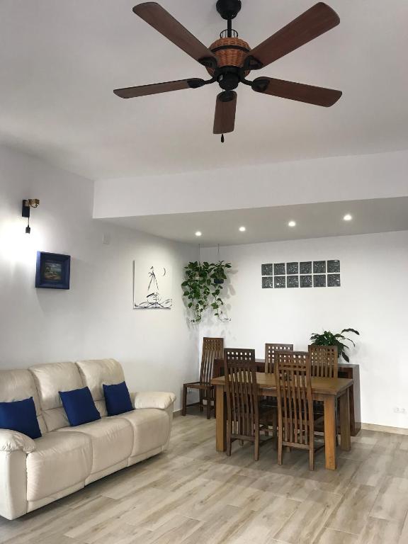 a living room with a ceiling fan and a table and chairs at Cal Morrudet in L'Ametlla de Mar