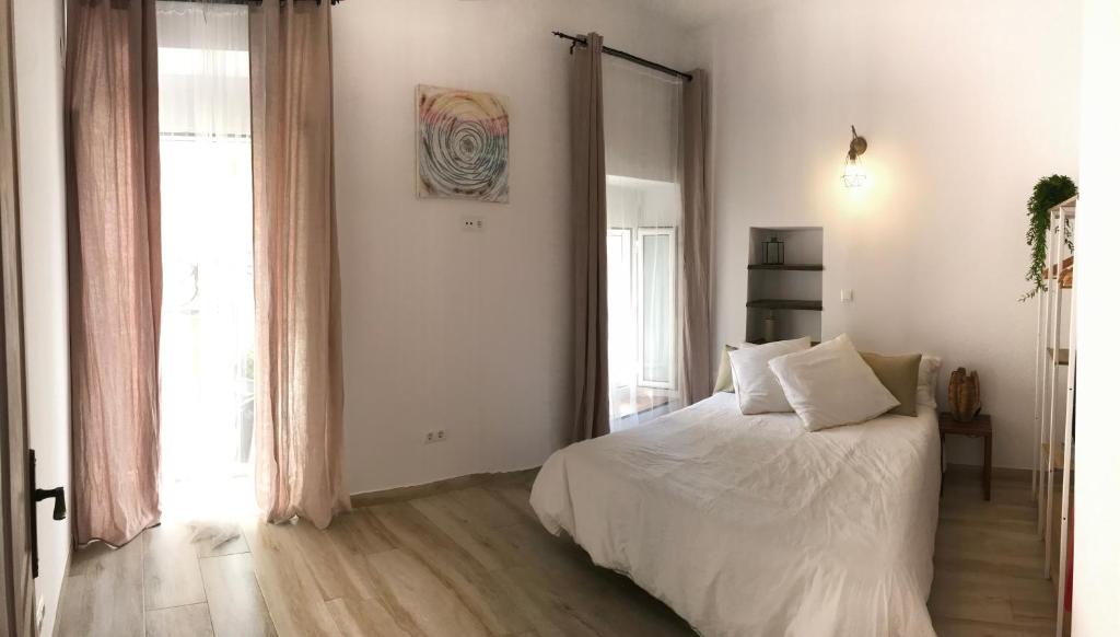 Un dormitorio con una cama blanca y una ventana grande. en Cal Morrudet, en L'Ametlla de Mar