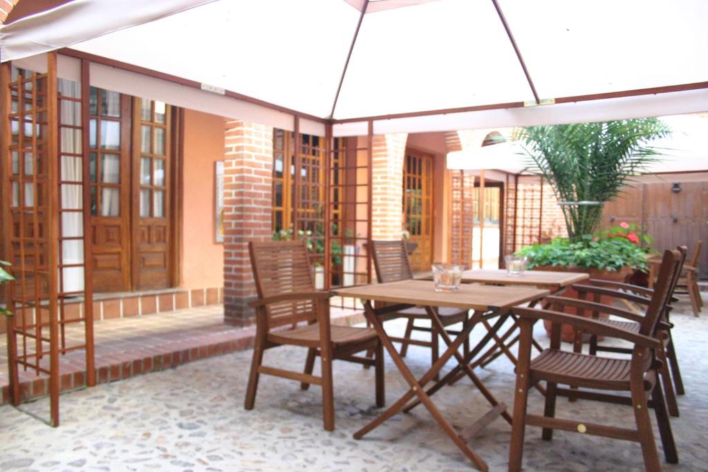 stół i krzesła z parasolem na patio w obiekcie Hostería de la Galería Cerdán w mieście Talavera de la Reina
