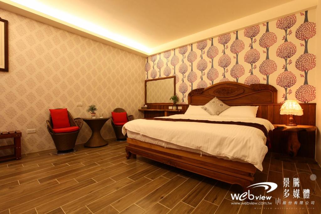 a bedroom with a bed and two red chairs at Marble House B&B in Dongshan