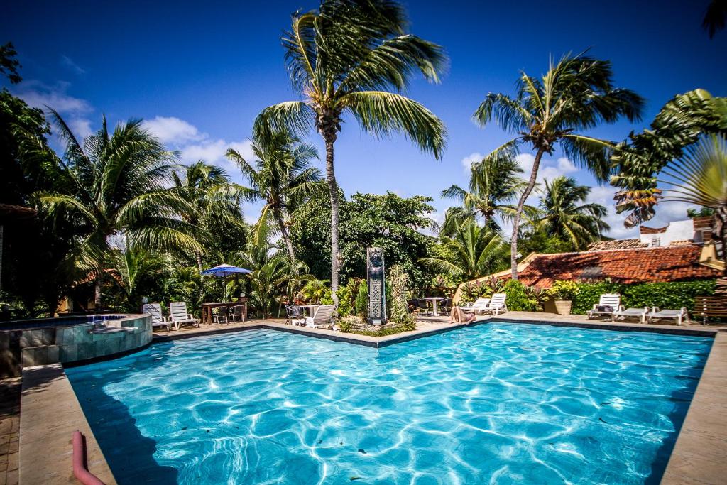 a pool at a resort with palm trees at Pousada Cavalo Marinho in Pipa