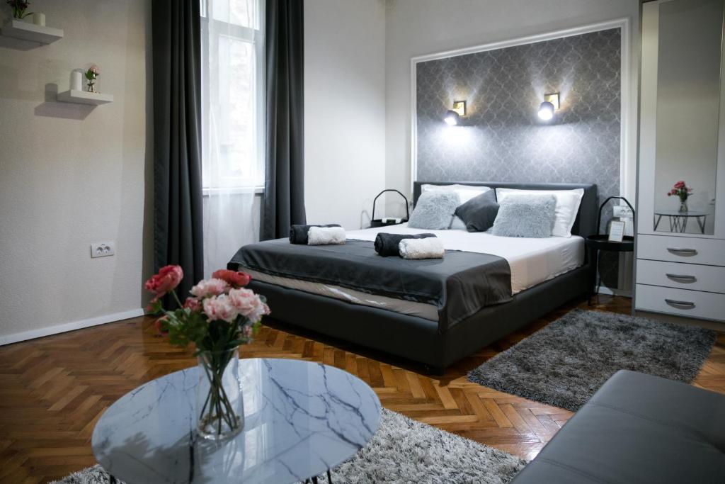 Un dormitorio con una cama y un jarrón de flores sobre una mesa. en Natalie's Place, en Belgrado