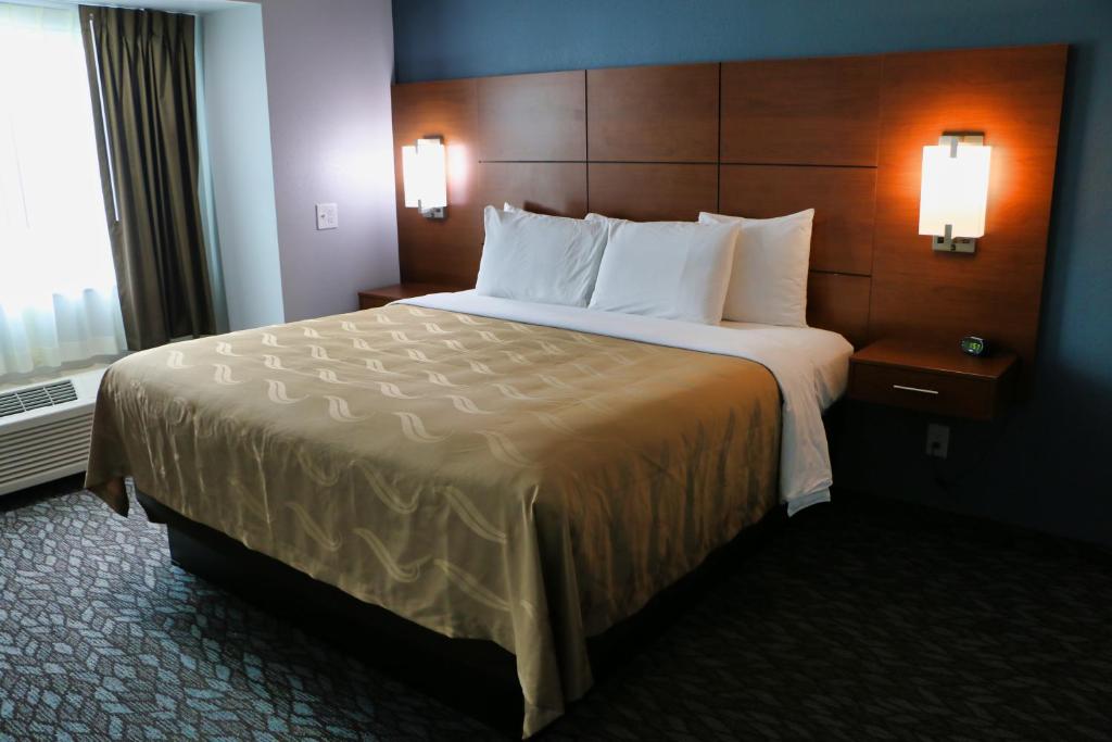 um quarto de hotel com uma cama grande com almofadas brancas em Quality Inn & Suites Watertown Fort Drum em Calcium