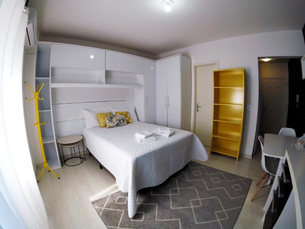 a bedroom with a white bed and a yellow closet at Studio Central XV Master Collection in Passo Fundo