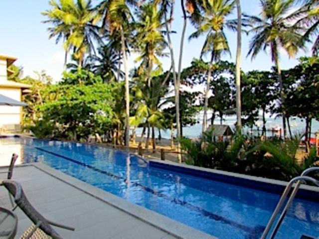 una piscina con palmeras junto a un complejo en Residencial Enseada Praia do Forte Apto 130, en Praia do Forte