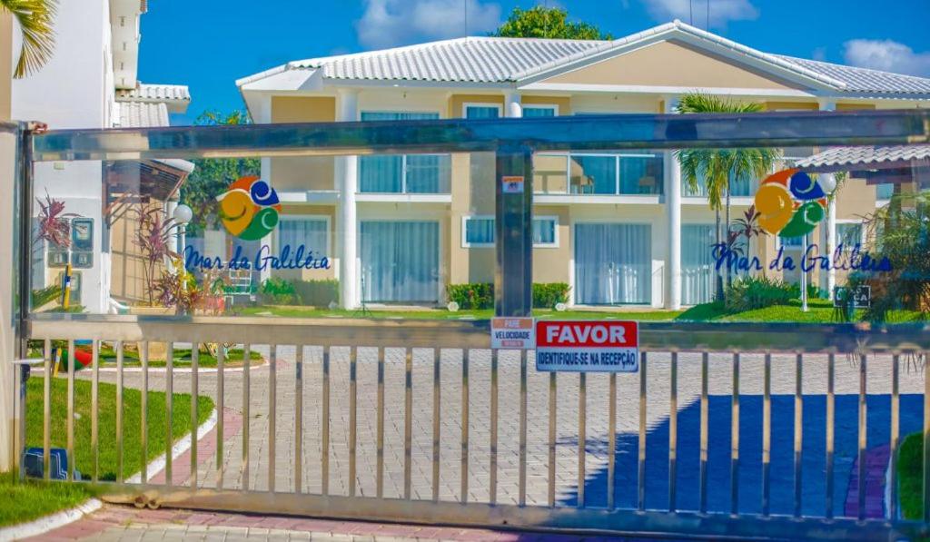 une clôture devant une maison avec un panneau dans l'établissement Residencial Mar da Galilei - Apartamento 20A, à Porto Seguro