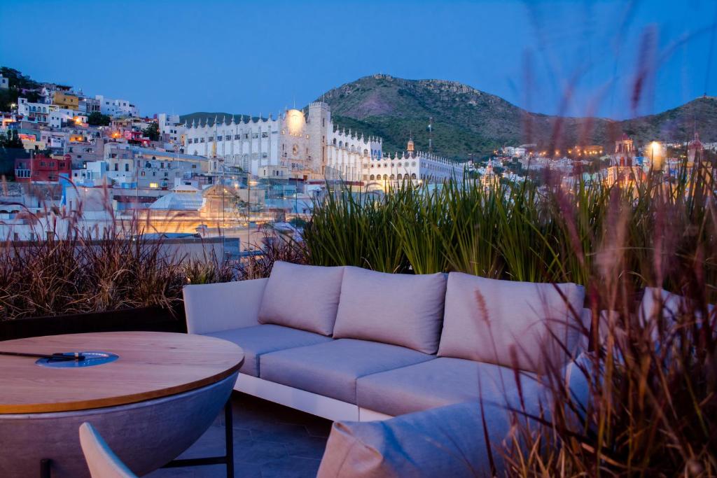 a couch sitting on a balcony with a view of a city at Antigua Trece Hotel Fusión in Guanajuato