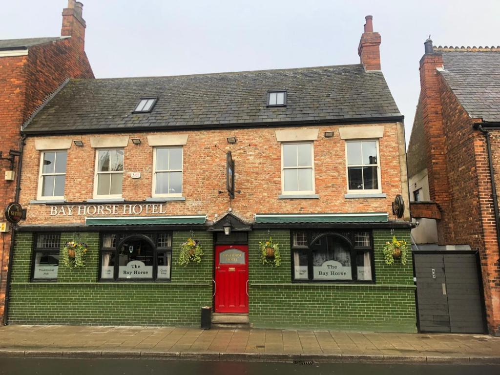 a brick building with a red door on a street at Bay horse hotel in Selby