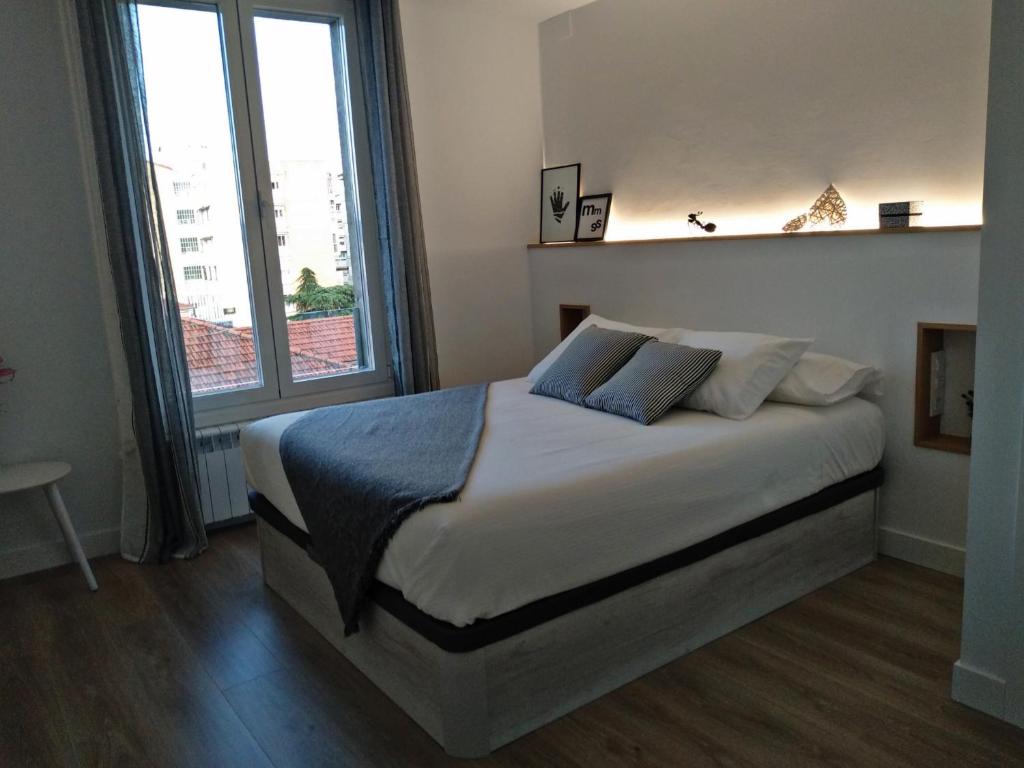a bedroom with a large bed and a large window at Morriña in Ourense