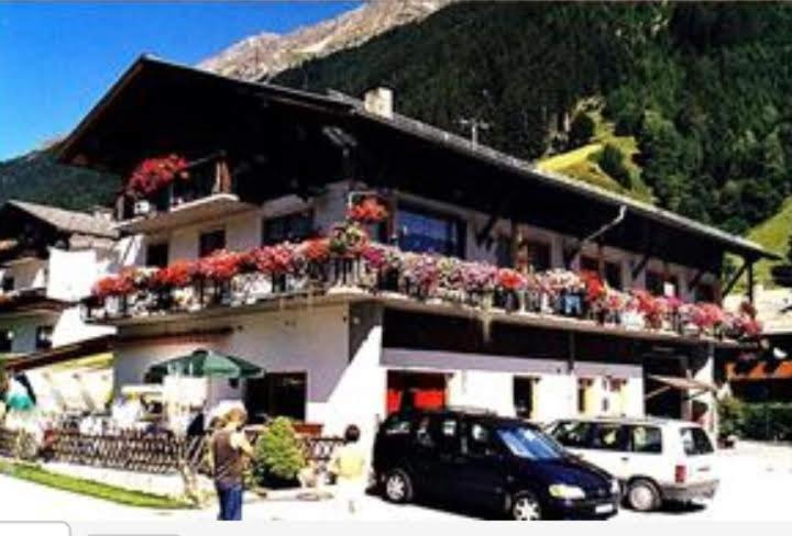 a man standing in front of a building with flowers at Pension Weber in Gries im Sellrain