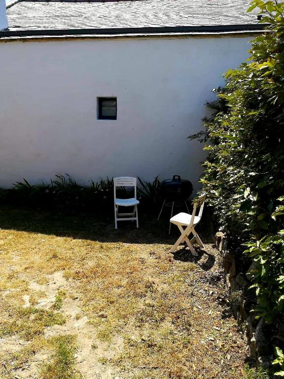 a white chair sitting next to a white building at Ty Biz in Saint-Jean-Trolimon