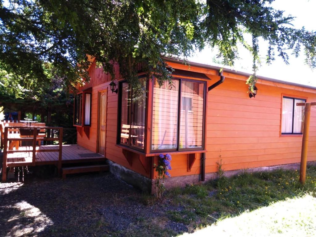 a small orange house with a porch and a deck at Cabañas gonzalez caniupan in Licán Ray