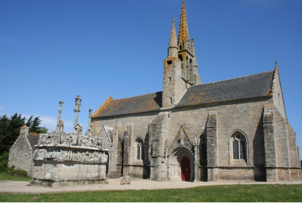 an old stone church with a tower and a red door at Ty Biz in Saint-Jean-Trolimon