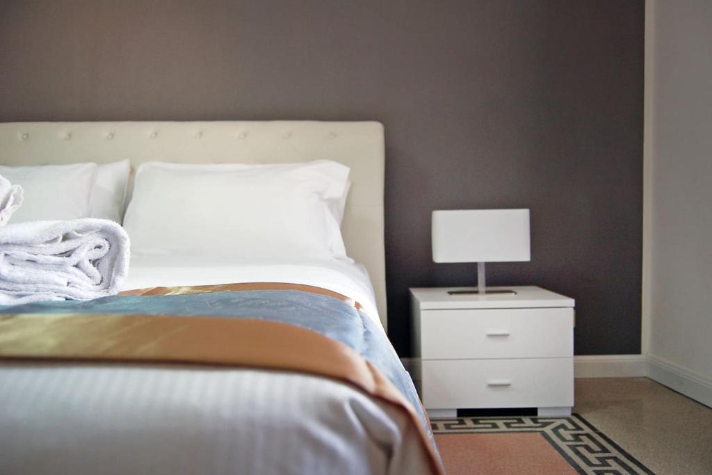 Un dormitorio con una cama y una mesita de noche con una lámpara. en Guardabassi Collection - Vatican White by Varental, en Roma