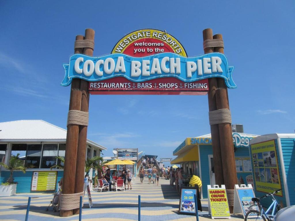 a sign for a beach pier with people walking under it at Cozy Beach Getaway in Cape Canaveral