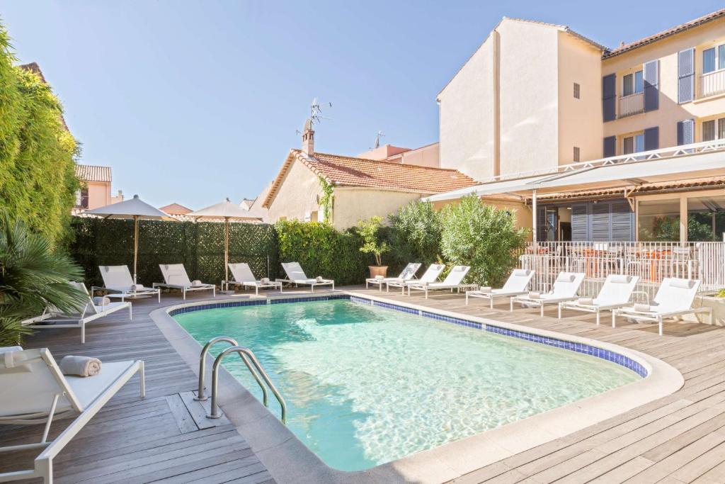 a swimming pool with lounge chairs and a house at Best Western Hotel Matisse in Sainte-Maxime