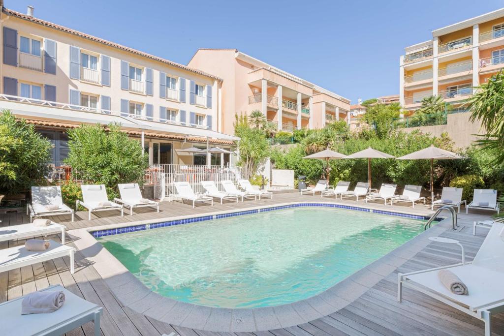 uma piscina com cadeiras e guarda-sóis num hotel em Best Western Hotel Matisse em Sainte-Maxime