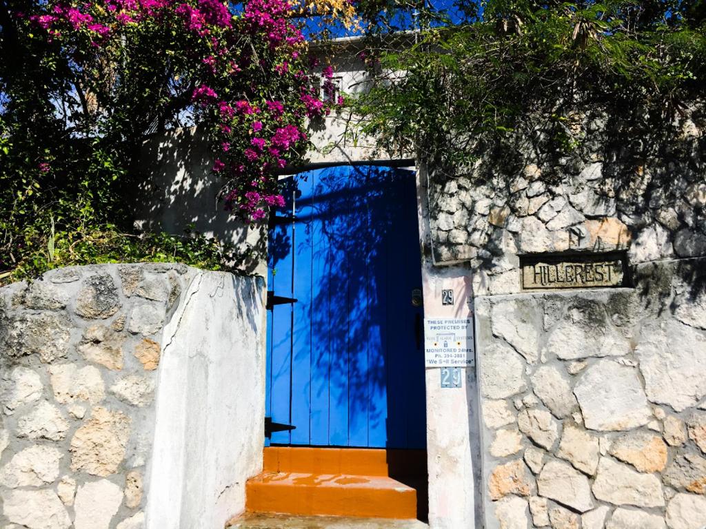 een blauwe deur in een stenen muur met roze bloemen bij Hillcrest in Nassau