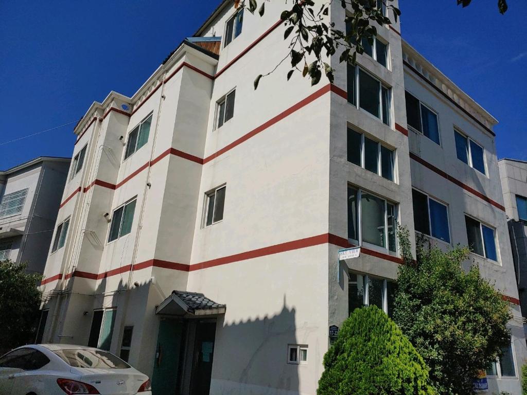 Un edificio con una striscia rossa e bianca sopra. di Gimhae Guest House a Gimhae