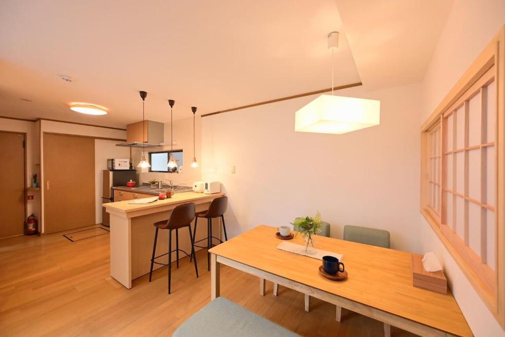 a kitchen and living room with a wooden table in a room at OMM STAY in Tokyo