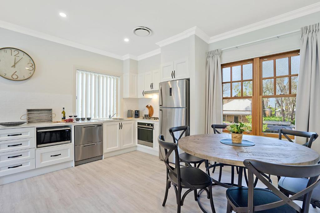 a kitchen with a table and chairs and a clock at Accommodation Hunter - Adams Street Maitland in Maitland
