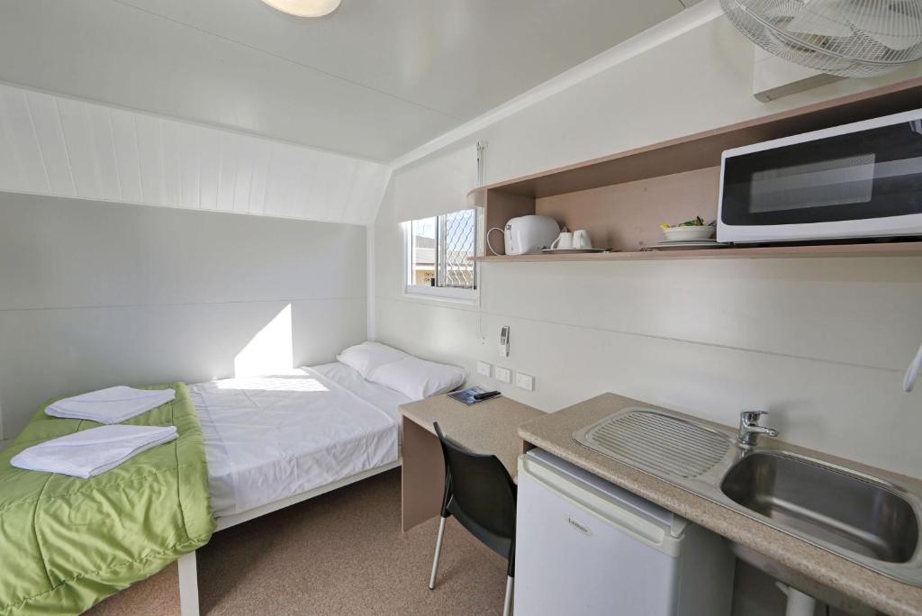 Kleines Zimmer mit einem Bett und einem Waschbecken in der Unterkunft Ned Kelly's Motel in Maryborough