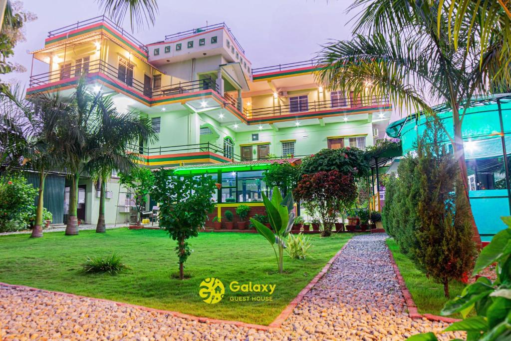 a building with palm trees in front of it at Galaxy Guest House in Bhairāhawā