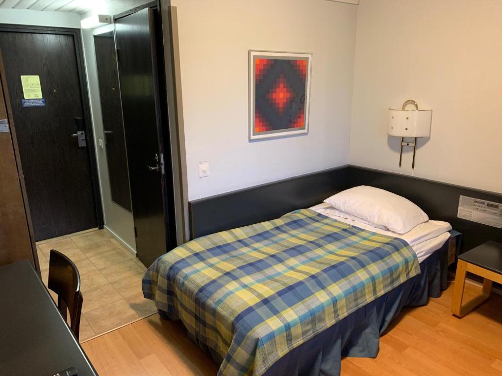 - une chambre avec un lit et une couverture tressée dans l'établissement Kylpylähotelli Kiannon Kuohut, à Suomussalmi