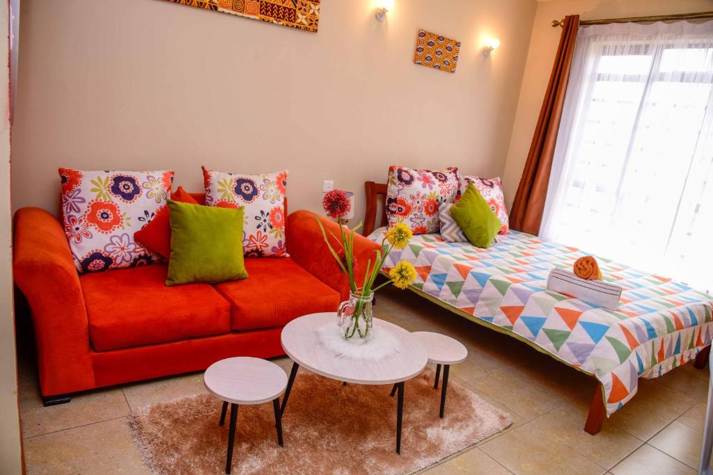 West Suites Sherry Homes في نيروبي: غرفة معيشة مع أريكة حمراء وطاولة