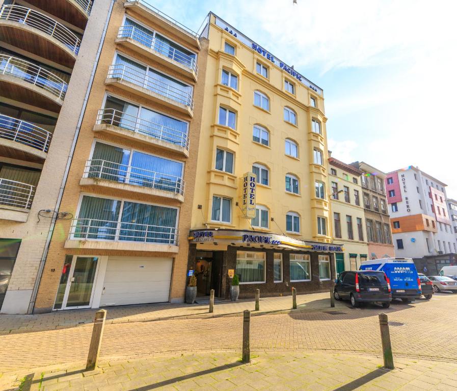 un bâtiment jaune dans une rue avec des voitures garées devant dans l'établissement Hotel Pacific, à Ostende