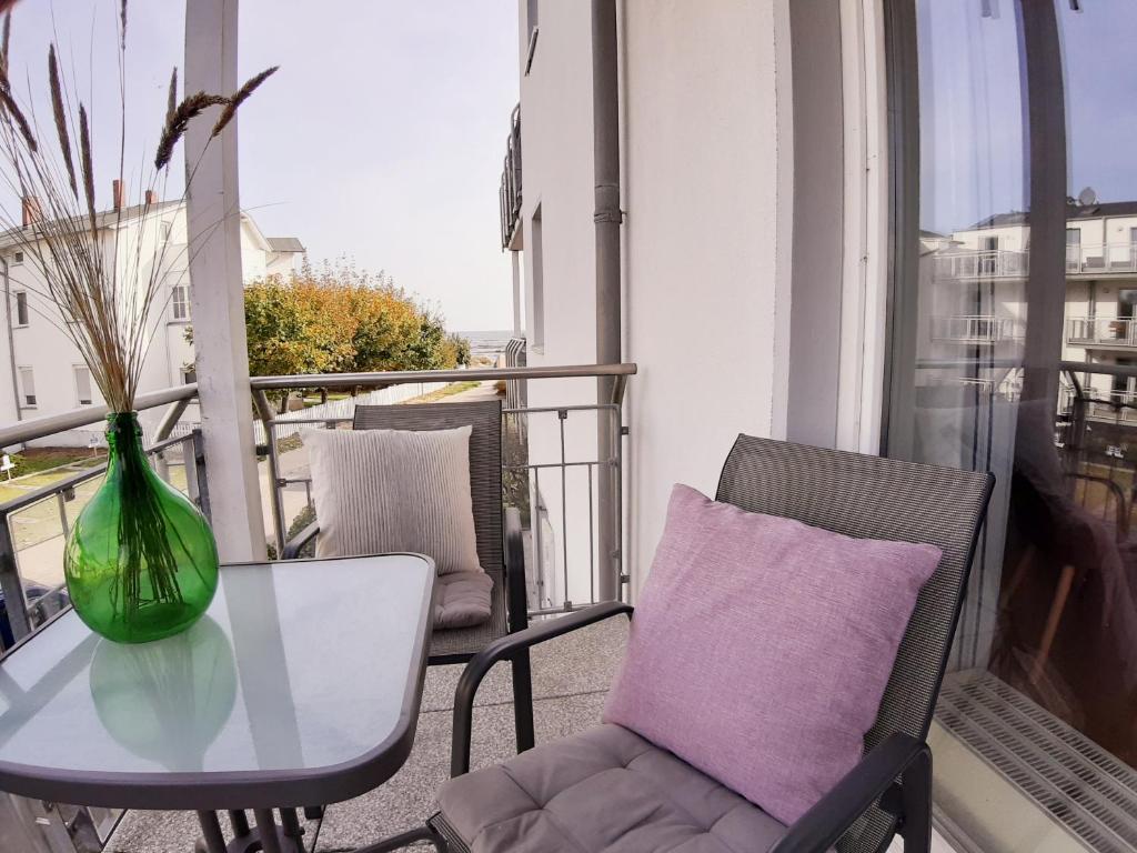 a table and chairs on a balcony with a vase at Am Strand in Juliusruh