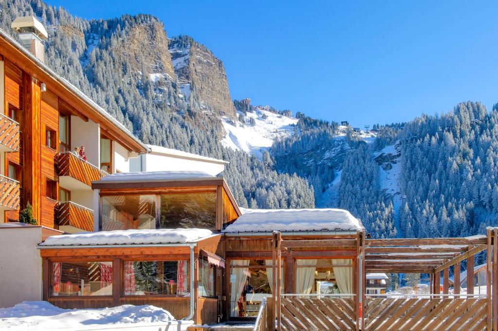 un bâtiment dans la neige avec une montagne en arrière-plan dans l'établissement Résidence Capfun du Téléphérique, Morzine, à Morzine