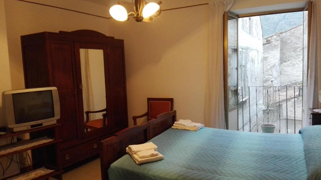 um quarto com uma cama, uma televisão e uma janela em B&B ERMINIA em Laino Borgo