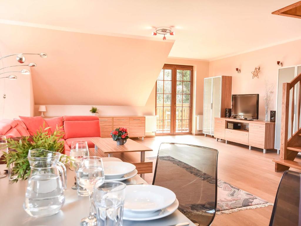 uma sala de estar com uma mesa e um sofá em VacationClub – Osiedle Podgórze 1C Apartament 22 em Szklarska Poręba