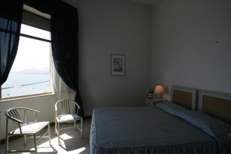 sypialnia z łóżkiem, 2 krzesłami i oknem w obiekcie Grand Hotel Fagiano Palace w mieście Formia
