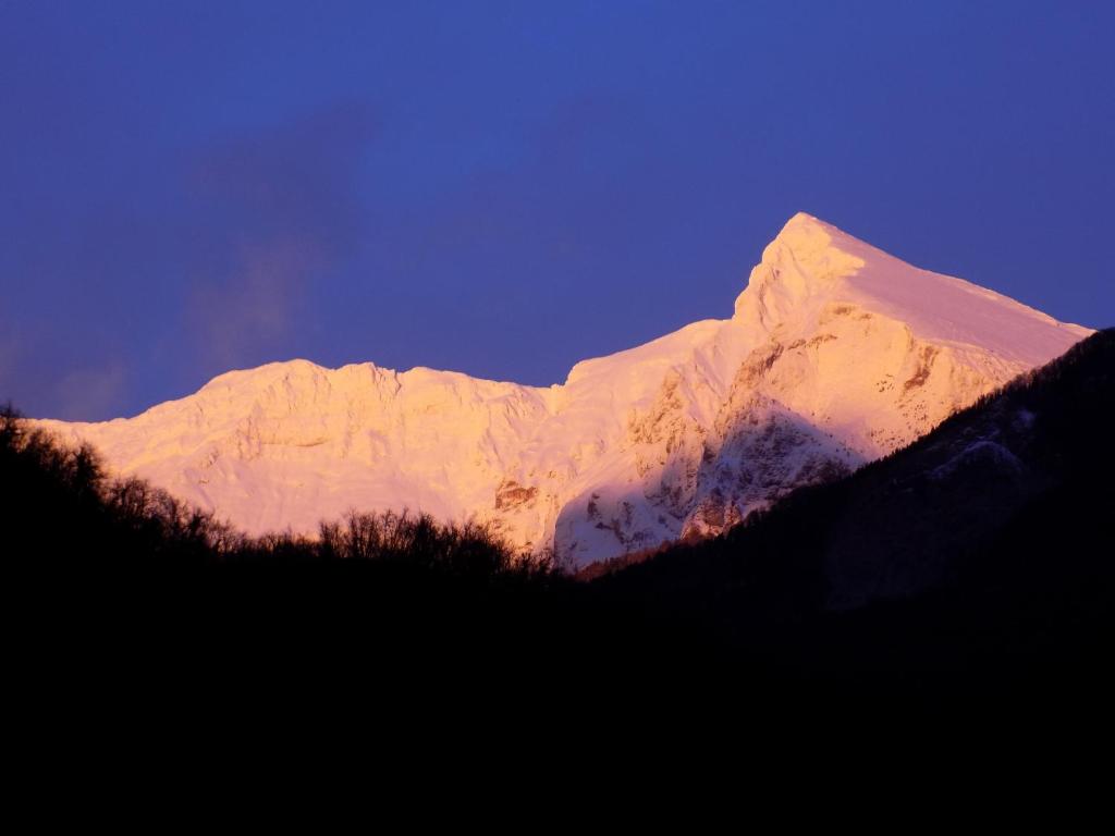 a snow covered mountain in front of a blue sky at Apartments Bobi in Tolmin