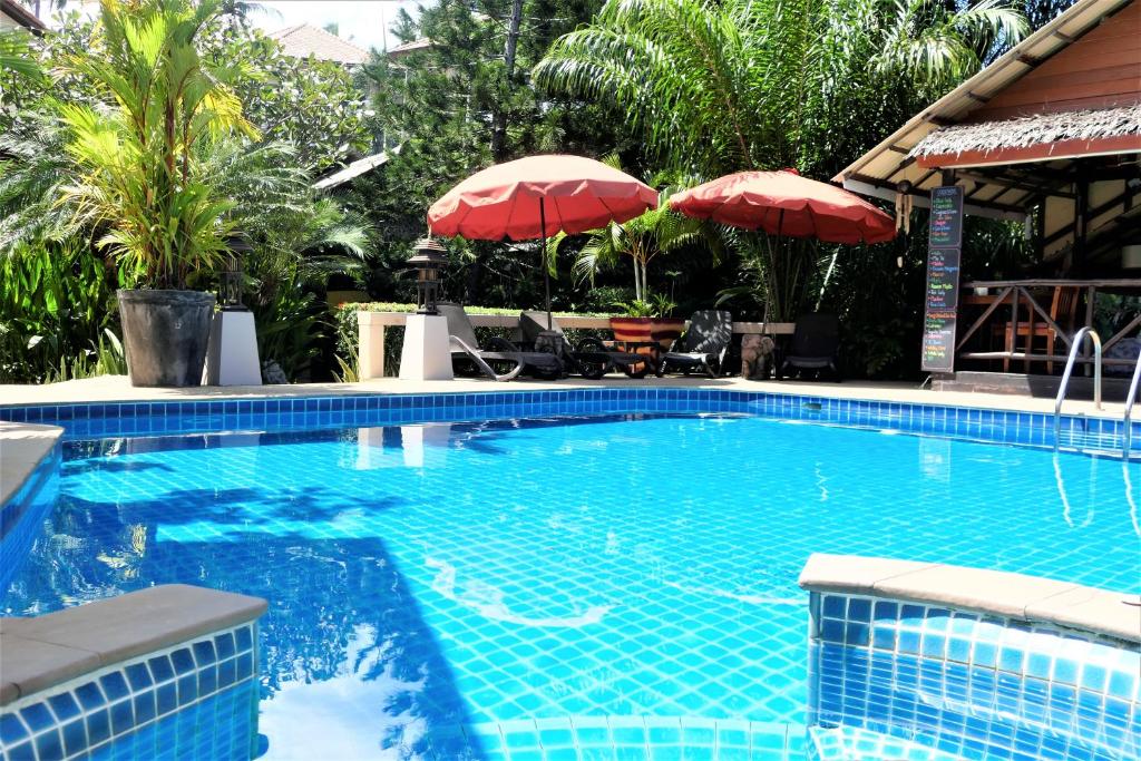 une grande piscine avec des parasols rouges dans un complexe dans l'établissement Baan Sukreep Resort, à Chaweng Noi Beach