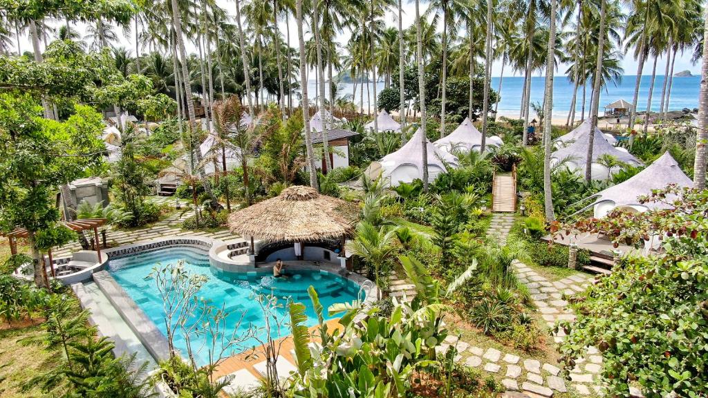 an aerial view of a resort with a swimming pool and palm trees at Nacpan Beach Glamping in El Nido