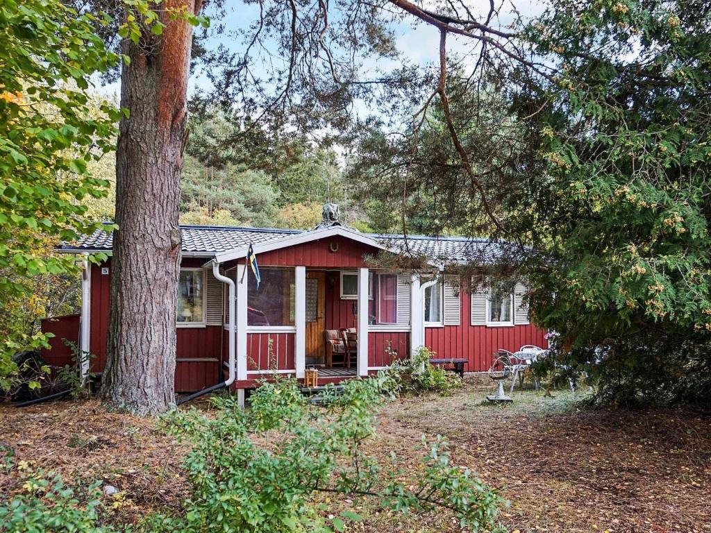 ein rotes Haus mit einem Baum davor in der Unterkunft 6 person holiday home in SORUNDA in Norra Svärdsö