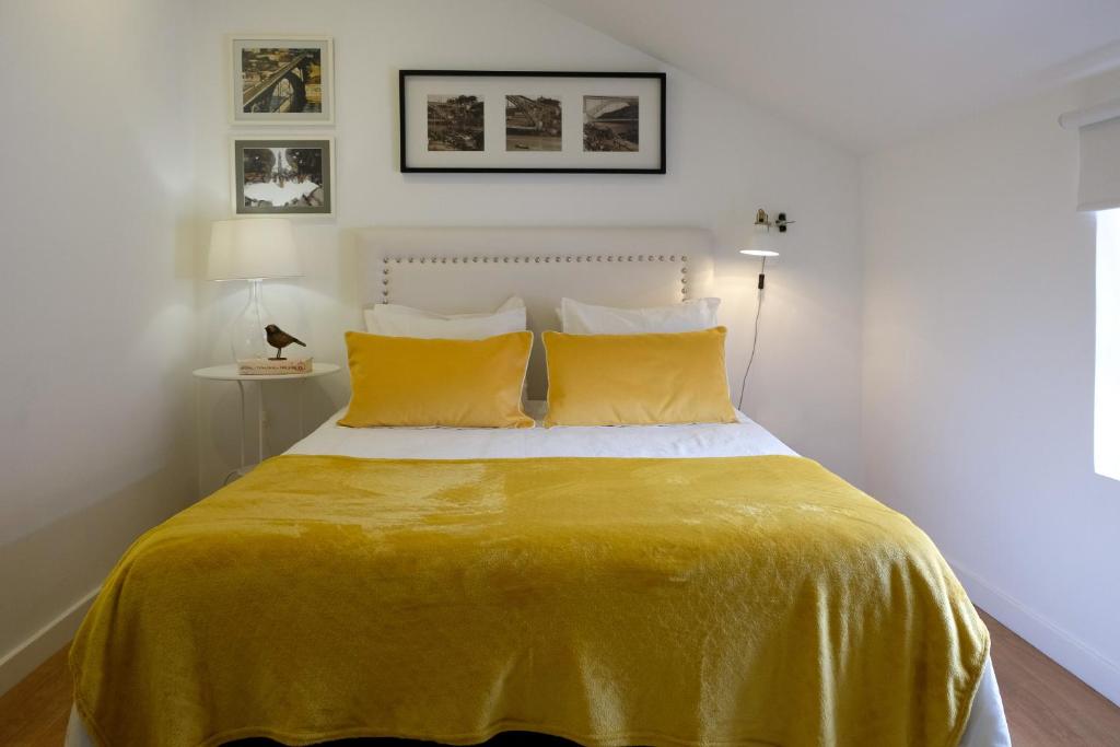 ein Schlafzimmer mit einem Bett mit einer gelben Decke in der Unterkunft Typical Village Oporto 24 in Porto