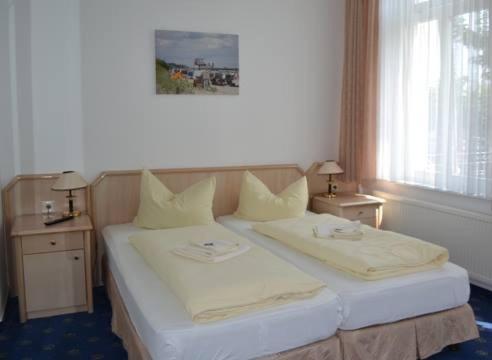a bedroom with a bed with two tables and a window at Pension Haus Pommern in Ahlbeck