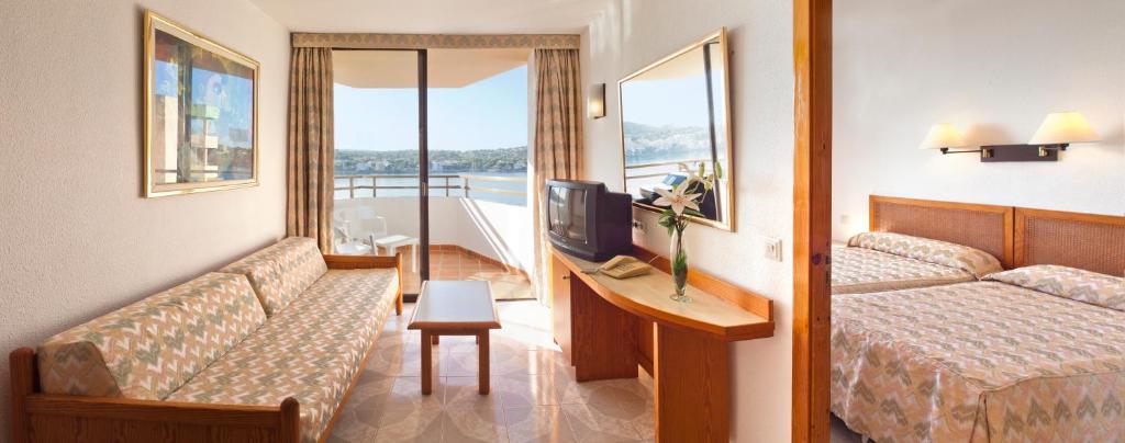 a hotel room with a bed, desk and a tv at TRH Jardín Del Mar in Santa Ponsa