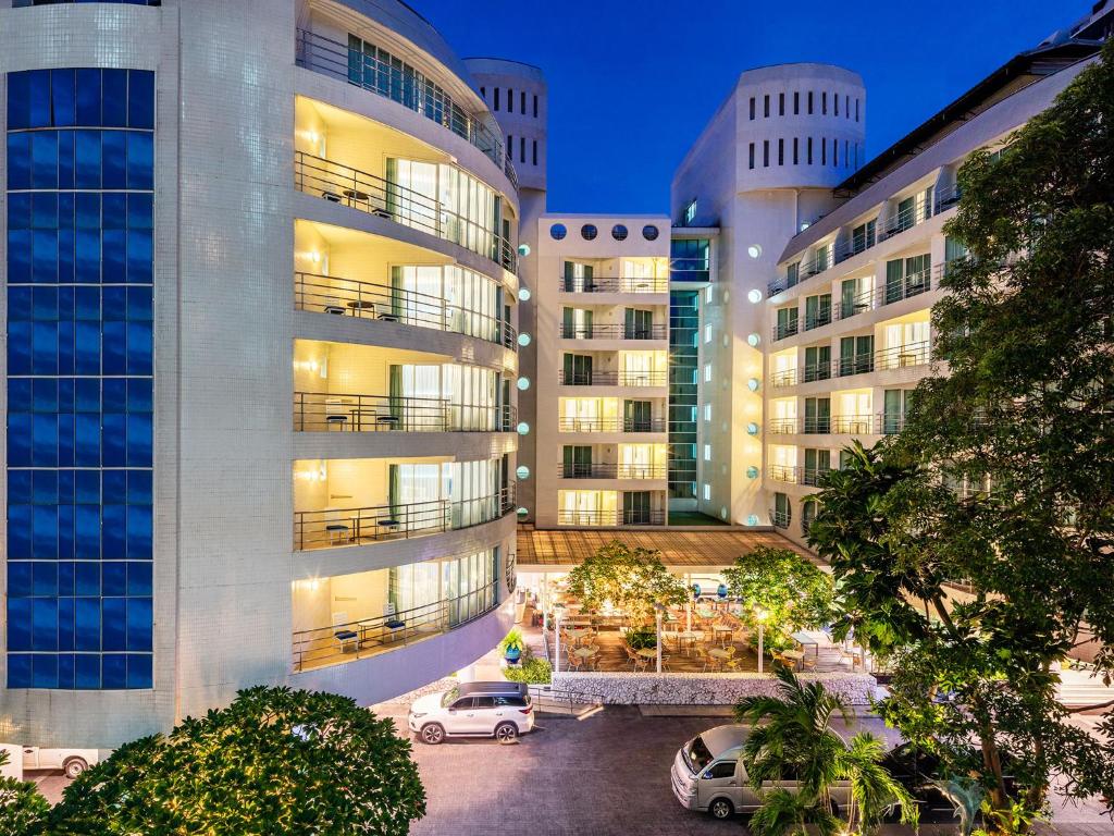 un edificio de apartamentos con coches aparcados en un aparcamiento en A-One New Wing Hotel en Pattaya centro