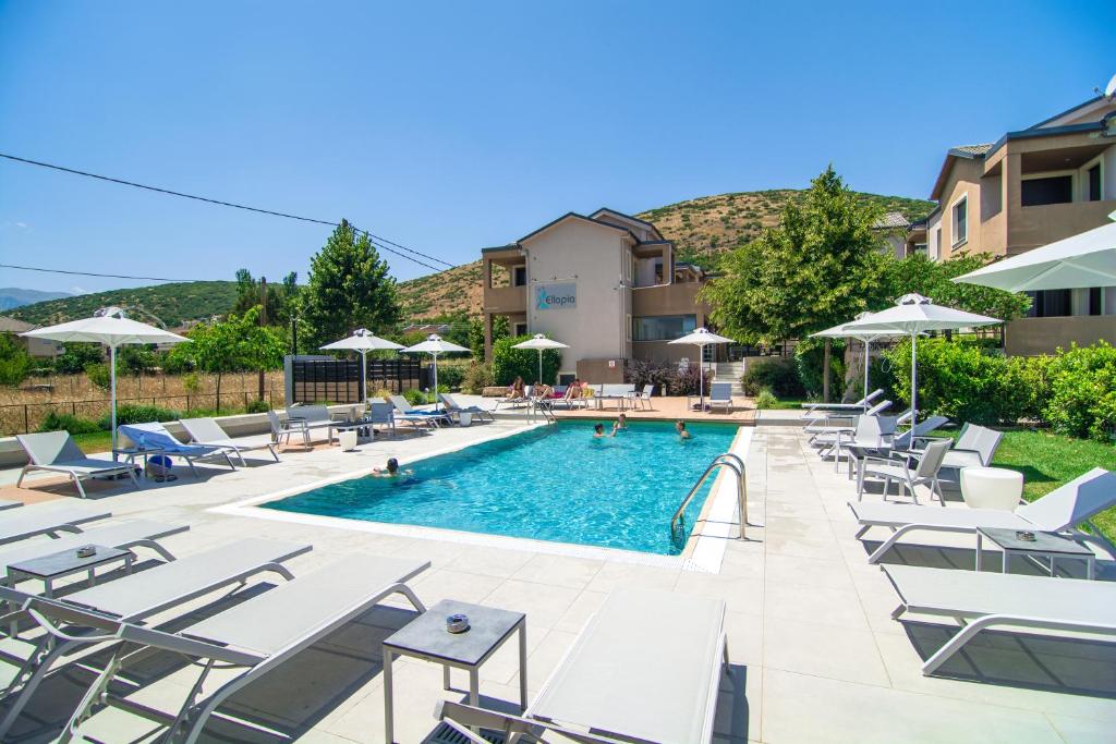 a swimming pool with lounge chairs and umbrellas at Ellopia Point Hotel in Ioannina