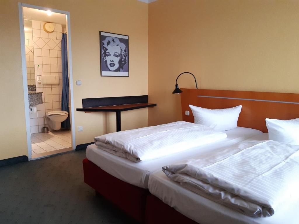 ein Schlafzimmer mit 2 Betten und einem Tisch sowie ein Badezimmer in der Unterkunft Good Morning + Leipzig in Leipzig