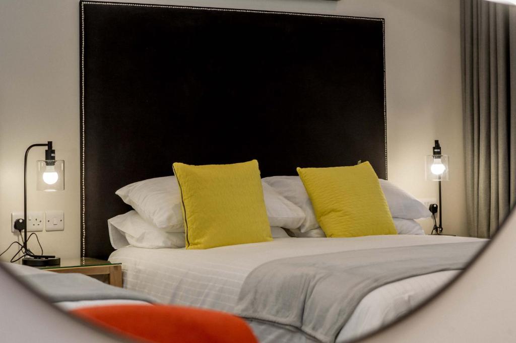 a bedroom with a bed with yellow pillows at The James Suites in Derry Londonderry