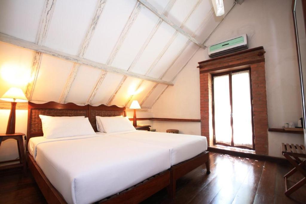 a bedroom with a large white bed and a window at Sala Prabang Hotel in Luang Prabang