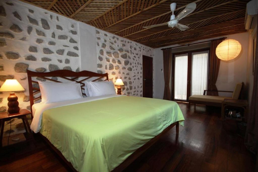 a bedroom with a bed with a green comforter at Sala Prabang Hotel in Luang Prabang